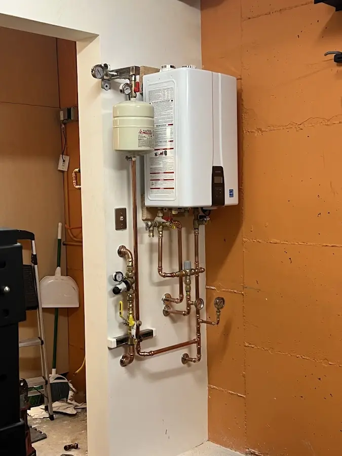 Plumbing technician inspecting water heater connections in Winton